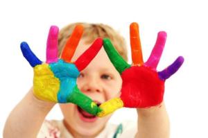 Five year old boy with hands painted in colorful paints ready for hand prints